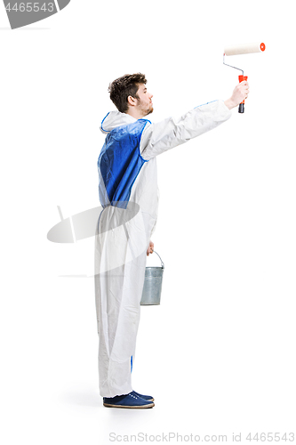 Image of Young male decorator painting with a paint roller climbed a ladder isolated on white background.