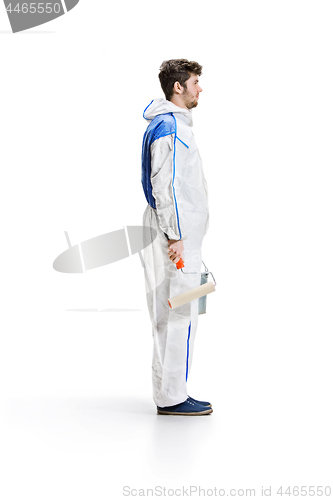 Image of Young male decorator painting with a paint roller climbed a ladder isolated on white background.