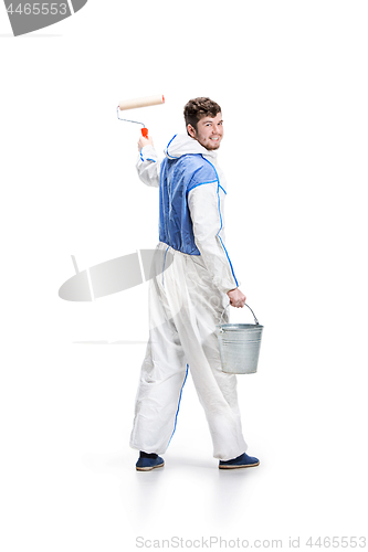 Image of Young male decorator painting with a paint roller climbed a ladder isolated on white background.