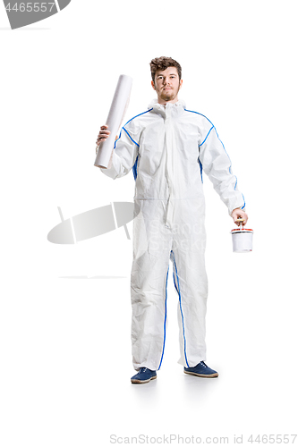 Image of Young male decorator painting with a paint roller climbed a ladder isolated on white background.