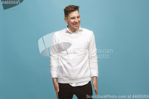 Image of The happy business man standing and smiling against blue background.