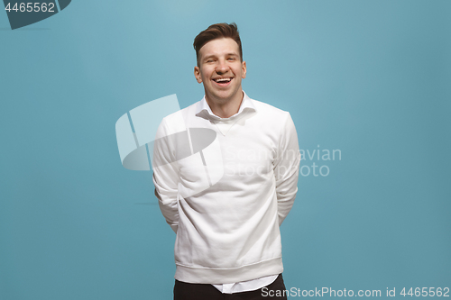 Image of The happy business man standing and smiling against blue background.