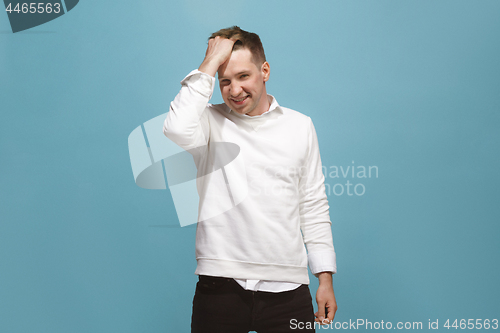 Image of The happy business man standing and smiling against blue background.