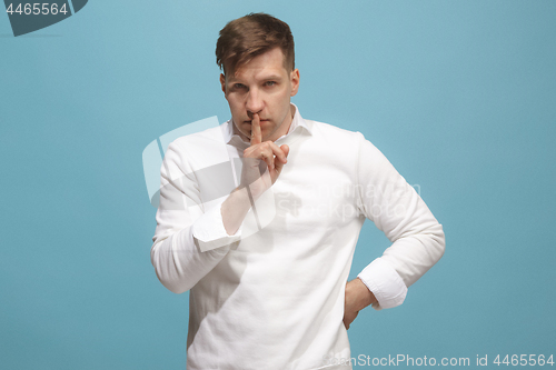 Image of The young man whispering a secret behind her hand over blue background