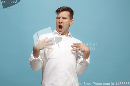 Image of Beautiful male half-length portrait isolated on blue studio backgroud. The young emotional surprised man