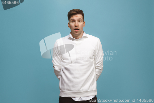 Image of The young attractive man looking suprised isolated on blue