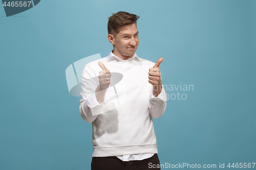 Image of The happy businessman standing and smiling against blue background.