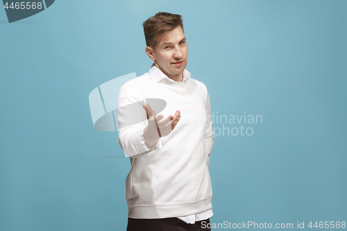 Image of The happy businessman standing and smiling against blue background.