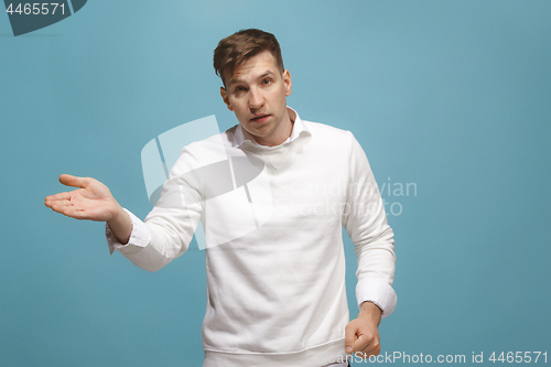 Image of Beautiful male half-length portrait isolated on blue studio backgroud. The young emotional surprised man