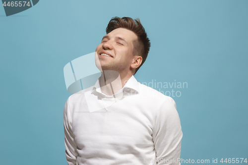 Image of The happy business man standing and smiling against blue background.