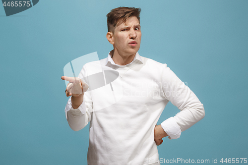 Image of Young man with disgusted expression repulsing something, isolated on the blue