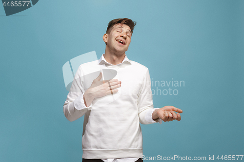 Image of The happy businessman standing and smiling against blue background.