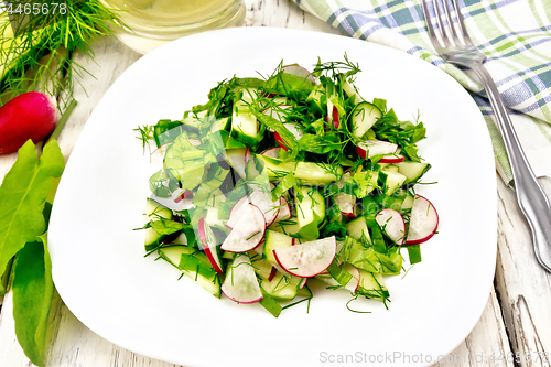 Image of Salad of radish and sorrel with oil in plate on light board