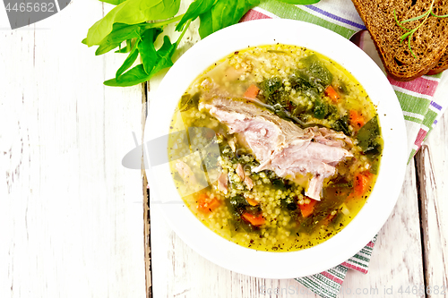 Image of Soup with couscous and spinach in plate on light board top