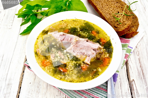 Image of Soup with couscous and spinach in plate on light board