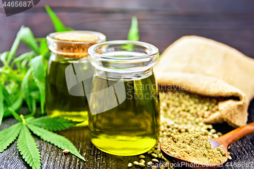 Image of Oil hemp in two jars and flour in spoon on wooden table