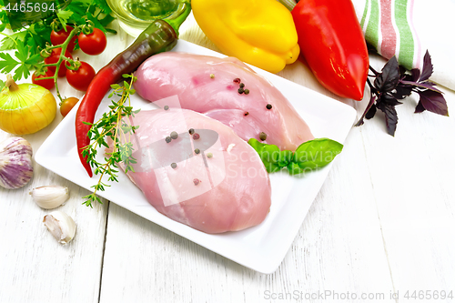 Image of Chicken breast raw in plate with vegetables and spices on board