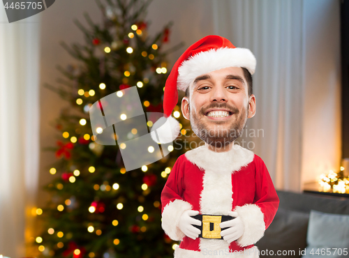 Image of smiling man in santa clothes over christmas tree