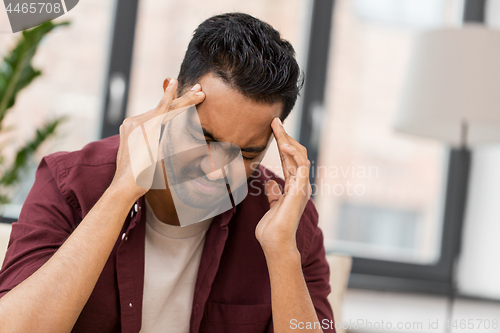 Image of unhappy man suffering from head ache at home