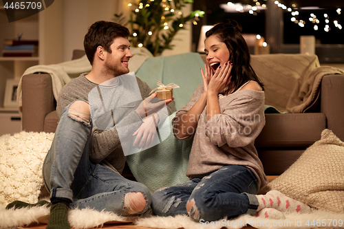 Image of happy couple with gift box at home