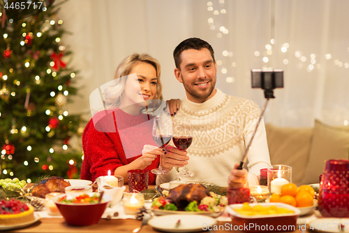 Image of couple taking picture by selfie stick at christmas