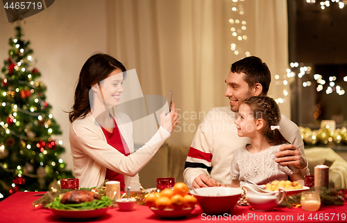 Image of happy family taking picture at christmas dinner