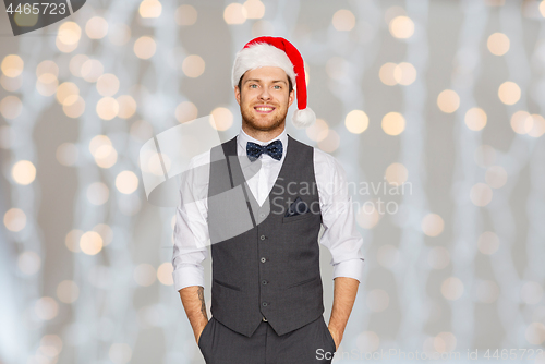 Image of happy man in santa hat and suit at christmas