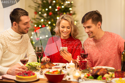 Image of friends with cellphone celebrate christmas at home