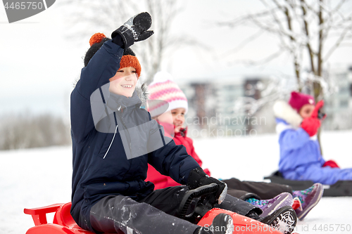 Image of happy kids sliding on sleds in winter