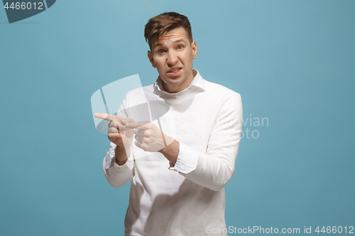 Image of Beautiful male half-length portrait isolated on blue studio backgroud. The young emotional surprised man