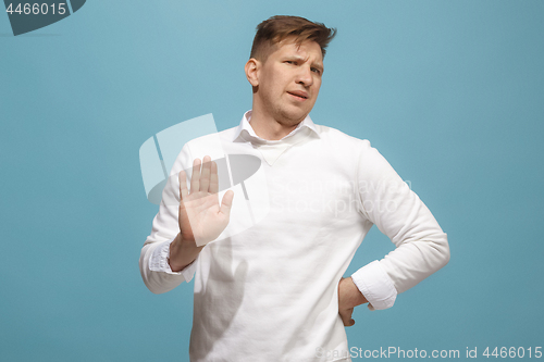 Image of Young man with disgusted expression repulsing something, isolated on the blue