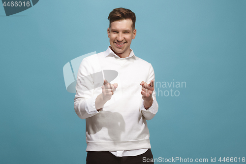 Image of The happy business man point you and want you, half length closeup portrait on blue background.