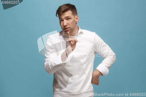 Image of Beautiful male half-length portrait isolated on blue studio backgroud. The young emotional surprised man