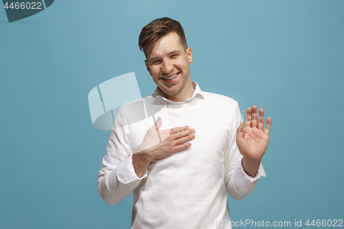 Image of The happy businessman standing and smiling against blue background.