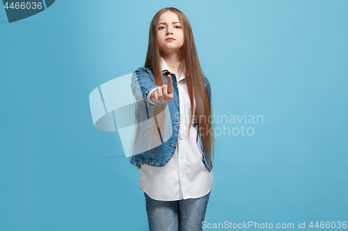 Image of The happy teen girl pointing to you, half length closeup portrait on blue background.