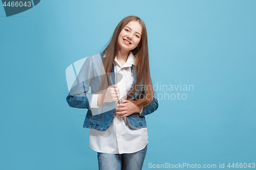 Image of The happy teen girl standing and smiling against blue background.