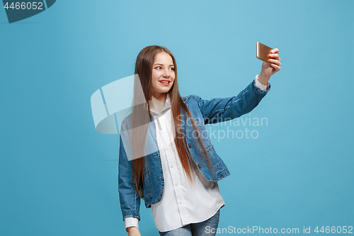 Image of The happy teen girl standing and smiling against pink background.