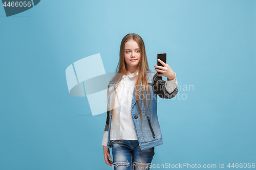 Image of The happy teen girl standing and smiling against pink background.