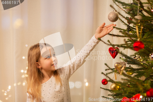 Image of happy girl in red dress decorating christmas tree