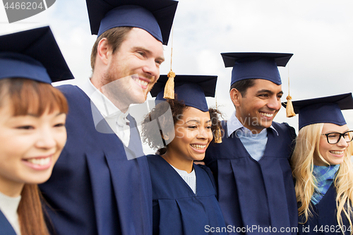 Image of happy students or bachelors in mortar boards