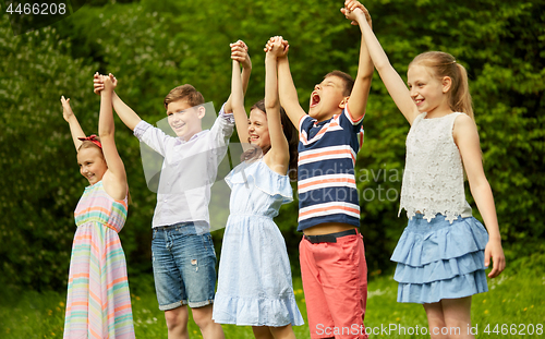 Image of happy kids holding raised hands in summer park