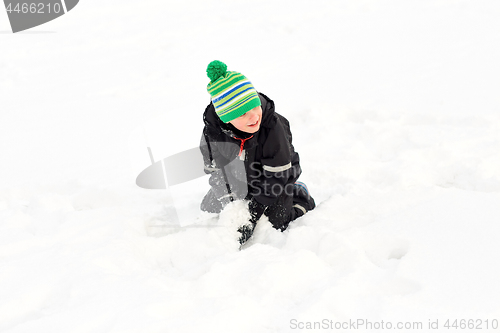 Image of happy little boy playing with snow in winter