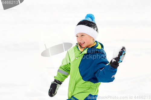 Image of happy boy playing and throwing snowball in winter