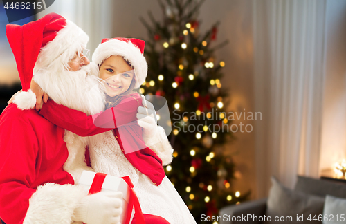 Image of girl hugging santa at home on christmas