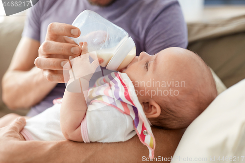 Image of close up of father feeding baby from bottle