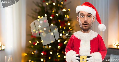 Image of surprised man in santa clothes over christmas tree