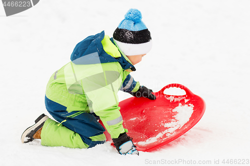 Image of happy boy with snow saucer sled in winter