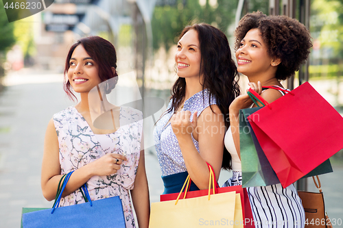 Image of happy women with shopping bags in city