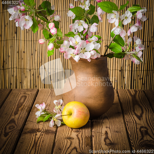 Image of Ripe apple and blossoming branch of an apple-tree in a clay jar,