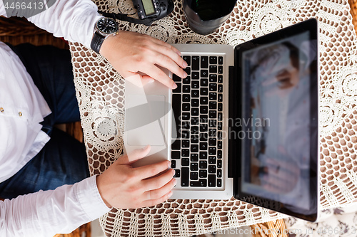 Image of man working with laptop computer and sitting on sofa